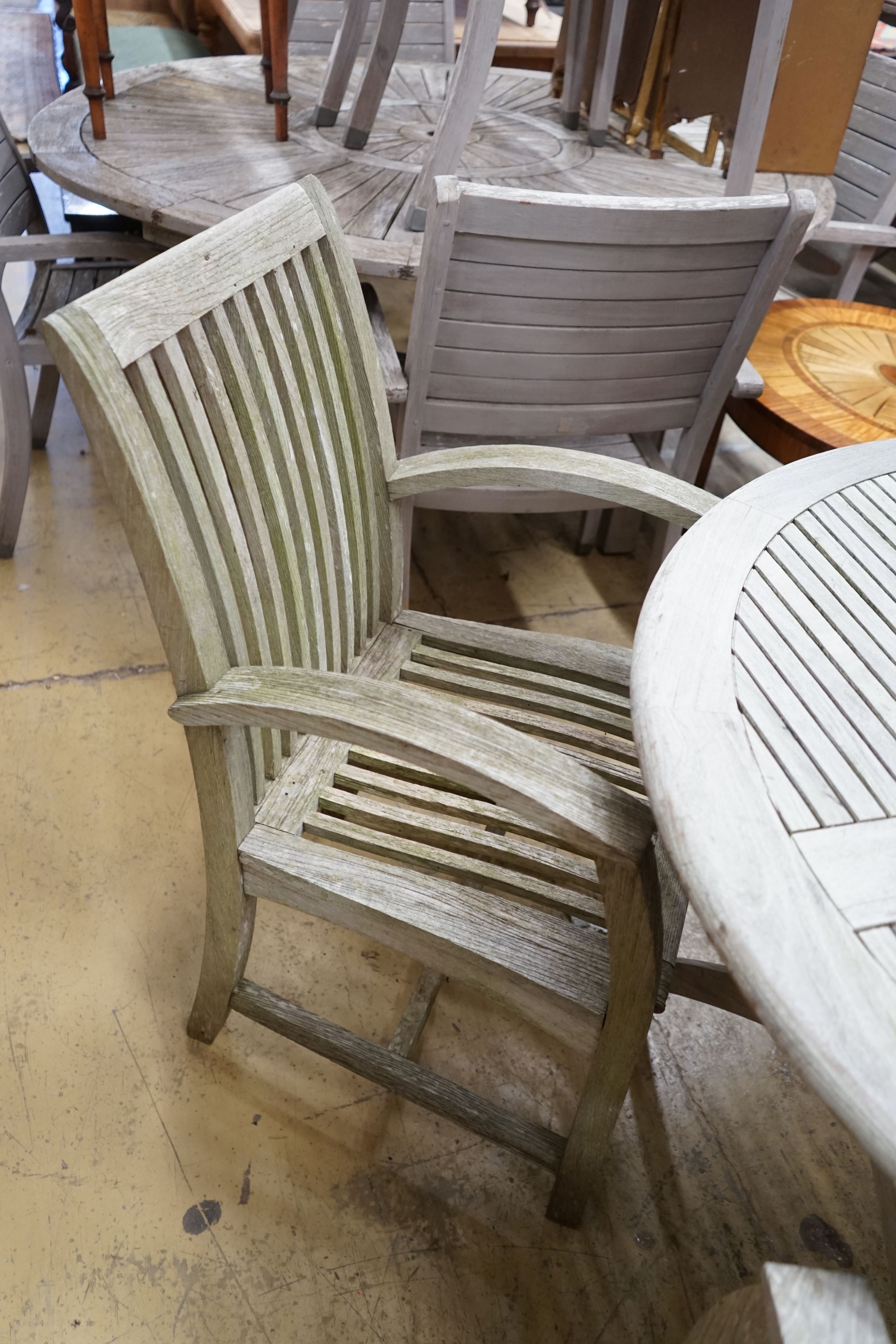 A circular weathered teak folding garden table, diameter 120cm, height 74cm and four teak chairs